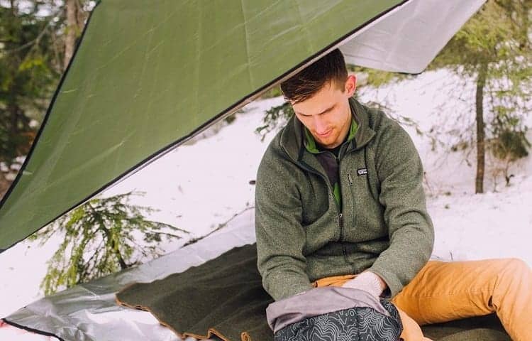 man sitting on survival blanket